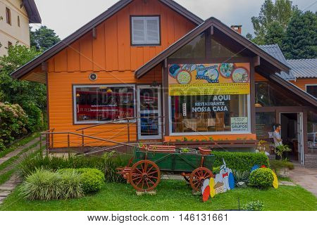 GRAMADO, BRAZIL - MAY 06, 2016: nice orange house with some plants and a cart on the front garden.