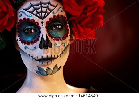 Woman in mexican santa muerte makeup looking at camera.