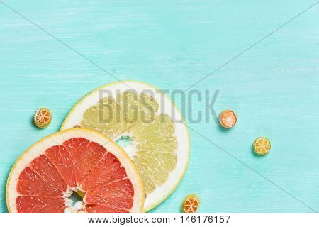 Top view on cut red and yellow grapefruit and small citrus candies on white wooden background. Juicy and fresh fruit. Healthy eating concept. Flay lay.