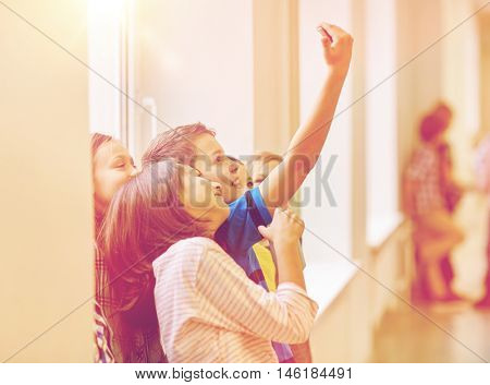 education, elementary school, drinks, children and people concept - group of school kids taking selfie with smartphone in corridor