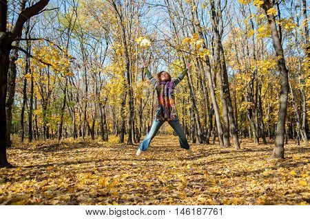 Joyful woman jumping for joy tossing up leaves
