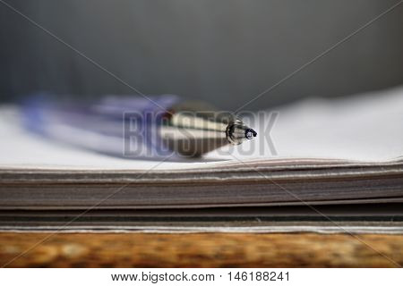 Detail of a sharp tip of the blue ball pen on the white lined notepad as a symbol of business office stationary