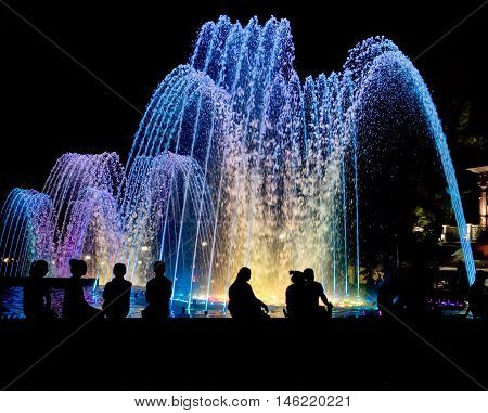 Night colored fountain with silhouettes of people.