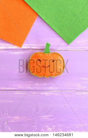 Halloween cute orange pumpkin on wooden background with blank place for text. Halloween children background. Handmade felt pumpkin decor