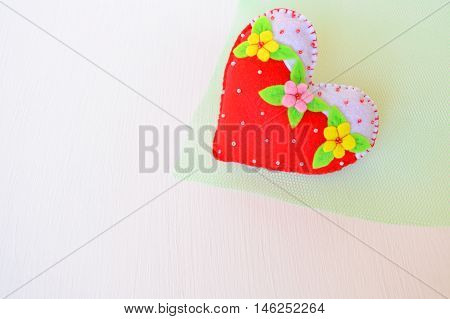 Hand made felt heart. Symbol of Valentines Day. Beautiful heart handmade on green and white background