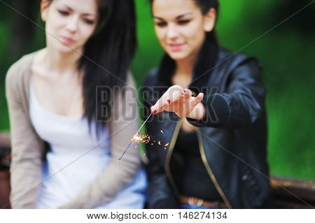 Portrait Of Happy Young Women Friends Laughing And Holding Sparklers In Outdoors. Friendship And Cel