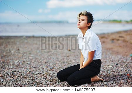 Young Beautiful Woman With Stylish Hairstyle In A White Shirt And Black Pants Sits On His Knees And