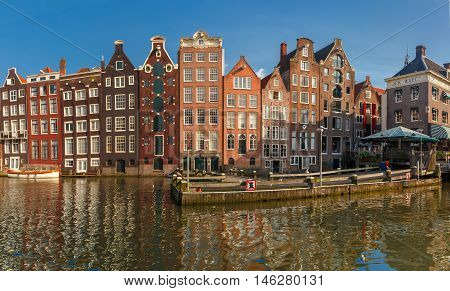 Panorama with beautiful typical Dutch dancing houses at the Amsterdam canal Damrak in sunny day, Holland, Netherlands.