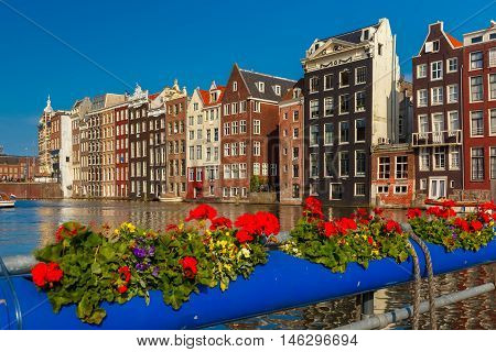 Beautiful typical Dutch dancing houses at the Amsterdam canal Damrak in sunny day, Holland, Netherlands.