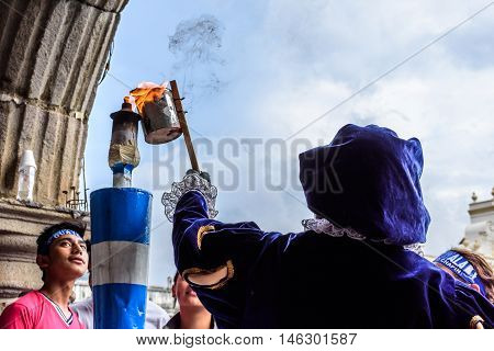 Antigua Guatemala - September 14 2015: Local dressed in colonial costume lights torch from flame in central park during Guatemalan Independence Day celebrations