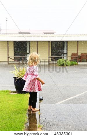 Photo of little girl standing under rain in Greymouth New Zealand.