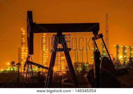 Oil rig silhouette at the background of refinery by night. Oil and gas industry.