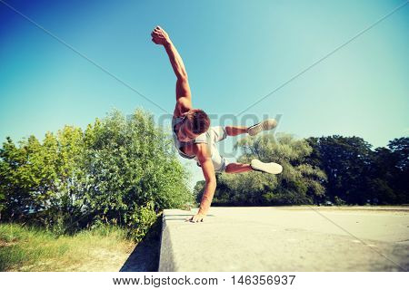 fitness, sport, parkour and people concept - young man jumping in summer park