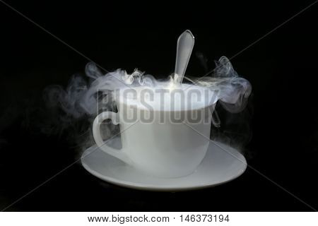 white cup with hot liquid and steam on black