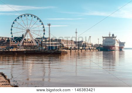 HELSINKI FINLAND - MARCH 17 2015: View of the Ferris wheel the port and Viking ferry with beautiful reflection on the sea in Helsinki Finland