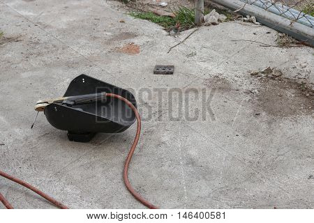 welding mask still life of rod-holder with cable and electrode for electric arc welding on a cement floor.
