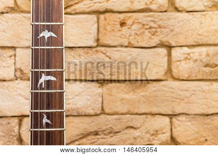 Wood guitar neck and brick on the  background