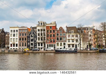 Amsterdam, Netherlands - April 2, 2016: Traditional old buildings, canal and boat in Amsterdam, the Netherlands