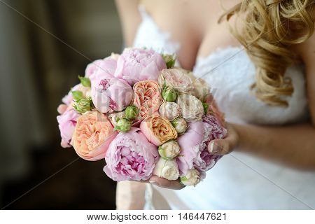 Beautiful bride is holding a wedding colorful bouquet. Beauty of colored flowers. Close-up bunch of florets. Bridal accessories. Female decoration for girl. Details for marriage and for married couple