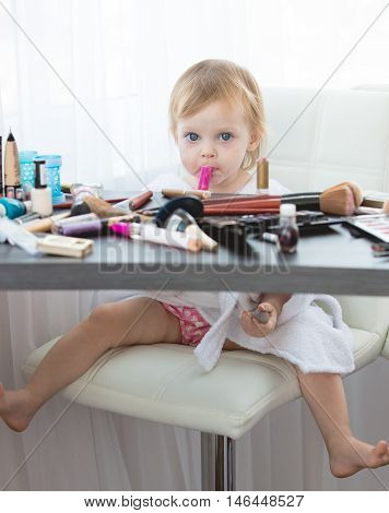 Little girl with cosmetics. Cute little girl with cosmetics and mirror playing at makeup table
