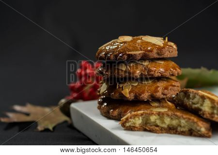 Typical Dutch filled spicy cookies with almonds on autumn colored and dark background