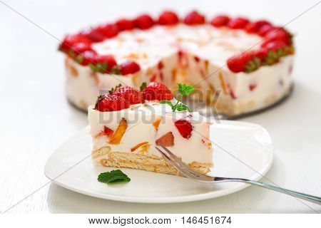 Cake with strawberries gelly yogurt and cherries. Surface view. Isolated on white background. One piece in a white plate