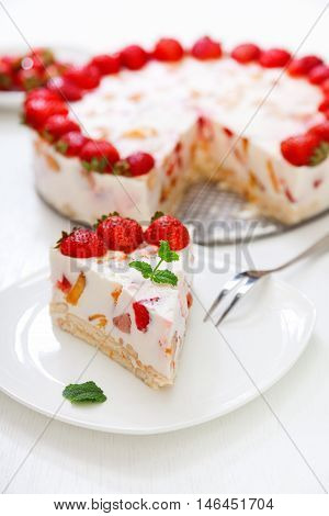 Cake with strawberries gelly yogurt and cherries. Surface view. Isolated on white background. One piece in a white plate. Vertical shot