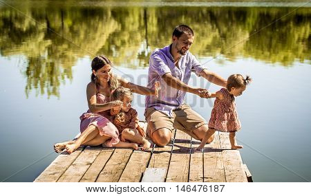Young Family On Pier Near Lake