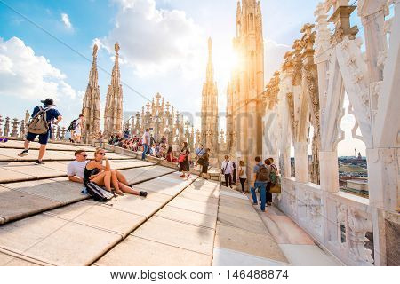 Milan, Italy - June 06, 2016: Tourists on the rooftop terrace of Duomo cathedral with beautiful decorated gothic spires. Duomo cathedral is the most famous sightseeing in Milan