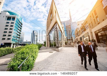 Milan, Italy - June 07, 2016: Businessmen walk on Vincenzo Capelli street with shopping boutiques and offices in Porta Nuova business district in Milan in the morning