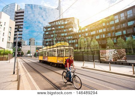 Milan, Italy - June 07, 2016: Modern residantial buildings with old tram and man on the bicycle in Porta Nuova business district in Milan in the morning