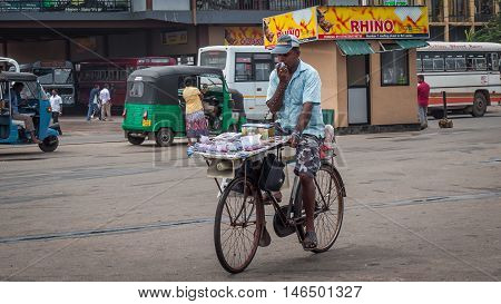 Matara Sri Lanka 27 May 2016: The seller of lottery tickets on a bicycle on the square near the central bus station of the city of Matara. Iprovizirovany office on wheels.