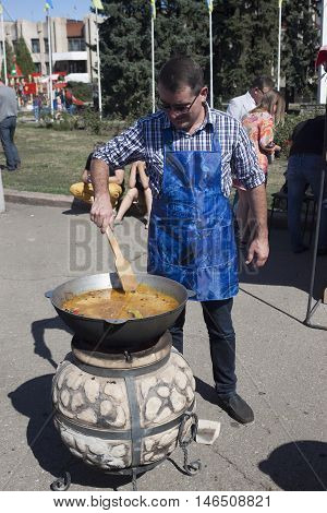 SLOVIANSK UKRAINE - SEPTEMBER 10 2016: Day of Sloviansk. Mayor Vadim M. Lyakh at the Sloviansk Cathedral Square prepares Uzbek pilaf