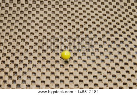 round yellow pushpin isolated on brown background