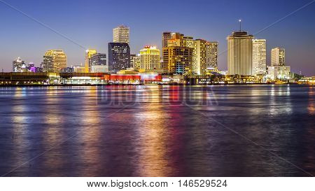 Downtown New Orleans skyline across the Mississippi River as night falls (Building logos blurred for commercial use)