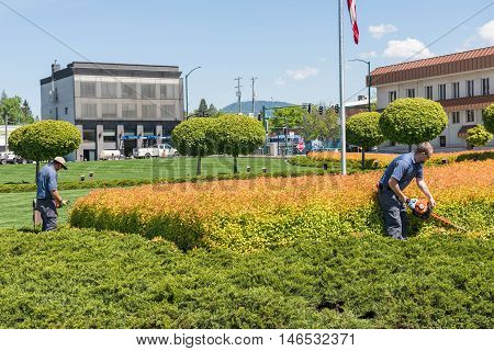 Coeur d'Alene, USA - May 3, 2016: Workers gardening and mowing shrubs by resort in downtown city