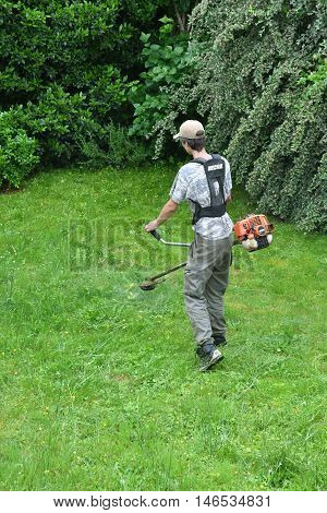 Verneuil sur Seine France - june 27 2016 :a woman is cutting lawn in a garden with a String trimmer