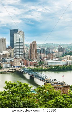Pittsburgh, USA - June 3, 2016: Vertical view of city cityscape or skyline with dark storm clouds, Smithfield street bridge and Monongahela river