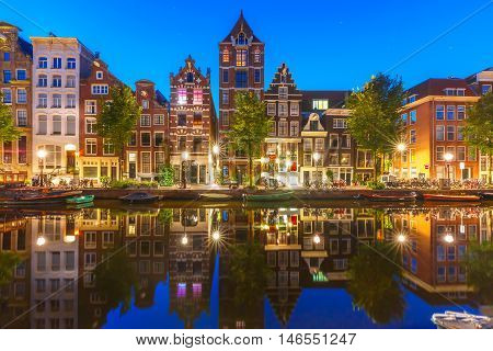Night city view of Amsterdam canal Herengracht with typical dutch houses and their reflections, Holland, Netherlands.