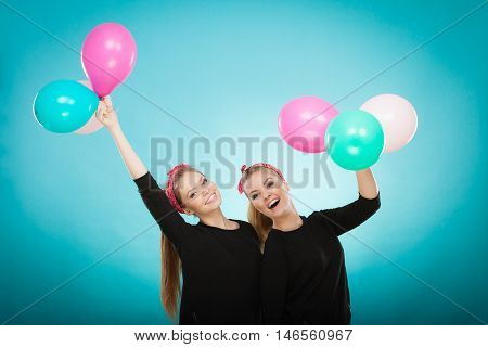 Memory of childhood and forgotten dreams. Two cute lovely retro styled women behave like little girls. Adults trying to fly away by balloons to dream come true.