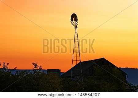 A beautiful sunrise on a rustic Amish barn with a windmill in Pennsylvania USA.
