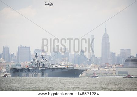 JERSEY CITY NJ - MAY 31 2016: USS Bataan (LHD 5) on the Hudson River passes the Empire State Building upon departing Manhattan marking the end of Fleet Week 2016 as seen from Liberty State Park.