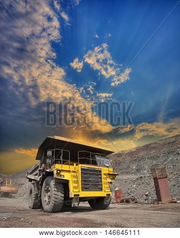 Mining truck loaded withiron ore driving along the opencast on sunset