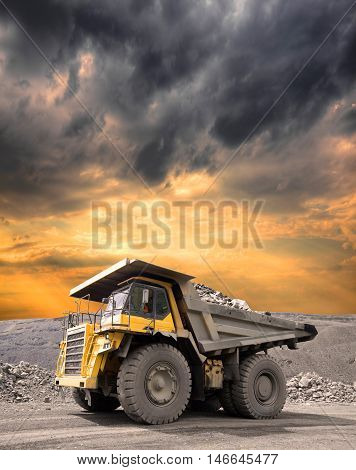Heavy mining truck driving through the iron ore opencast on stormy sunset