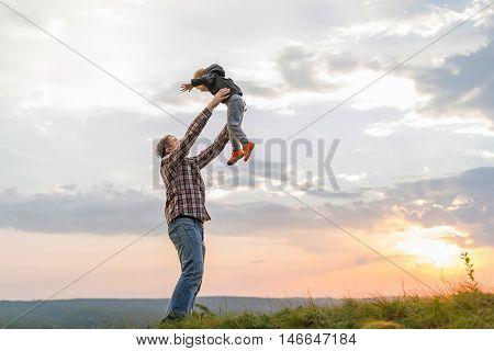Father tossing up his son. High on a hill in the evening soltse. The concept of oneness with nature family relationships and values. Camping. Playing with your child. Flight and fun. Confidence.