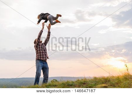 Father tossing up his son. High on a hill in the evening soltse. The concept of oneness with nature family relationships and values. Camping. Playing with your child. Flight and fun. Confidence.