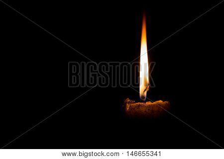 light of yellow candle at night on black background