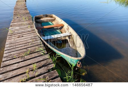 Fishing boat moored at a pier on the lake in the morning in summer sunny day