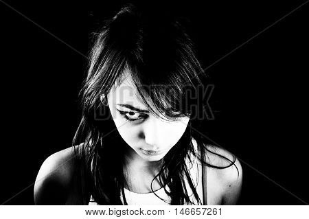 Heavily made-up teen girl looks angry over black background