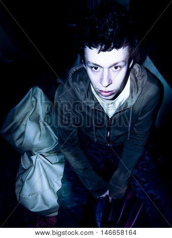 Drunk young man staring forward, flashlight used